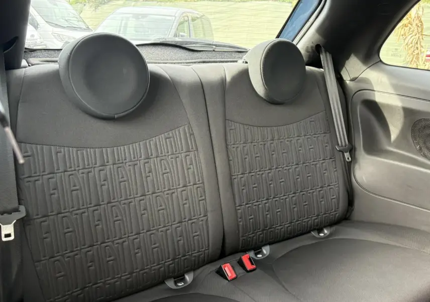 Vue intérieure sur la banquette arrière noire avec motif FIAT embossé, ceintures et appuie-têtes ronds visibles.