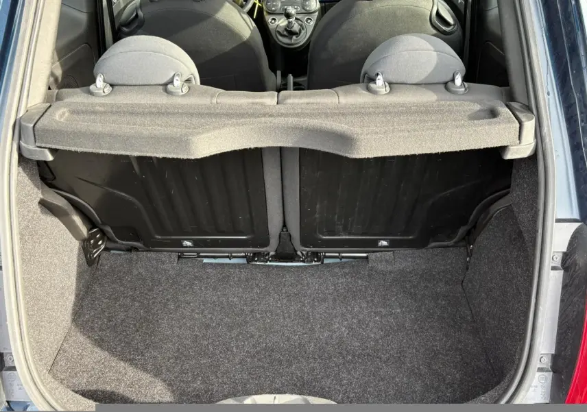 Vue du coffre ouvert d'une Fiat 500 Hybrid 70 bleu Dipinto, montrant l'intérieur et les dossiers des sièges arrière.
