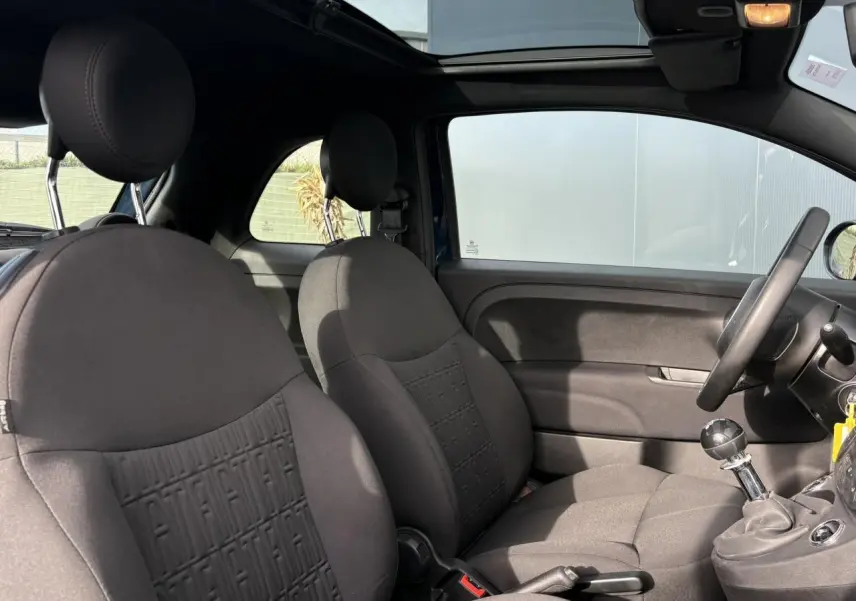 Vue intérieure côté droit de la Fiat 500 Hybrid 70 2024 avec sièges tissu noir et toit panoramique ouvert.