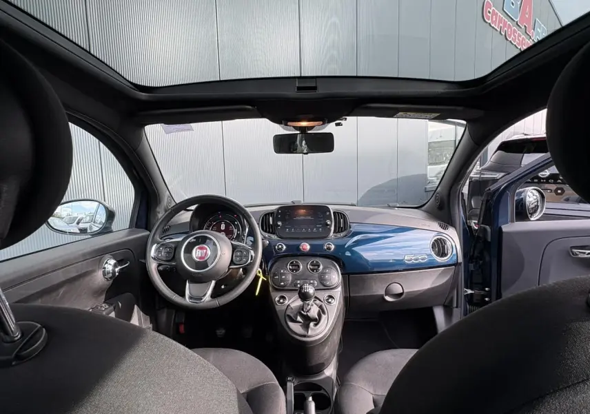Vue intérieure avant de la Fiat 500 Hybrid 70 bleu Dipinto avec tableau de bord brillant et toit panoramique.