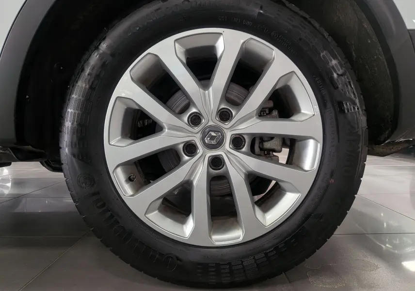 Gros plan sur la jante alliage argentée avec logo Renault au centre, montée sur un pneu Continental du Renault Kadjar blanc.