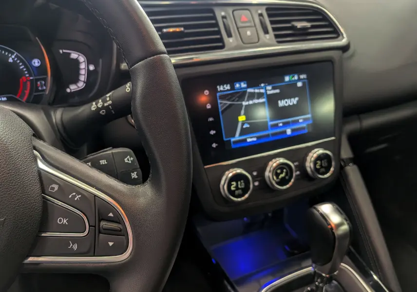 Vue intérieure côté conducteur du Renault Kadjar blanc glacier 2021, avec tableau de bord numérique et écran tactile central allumé.