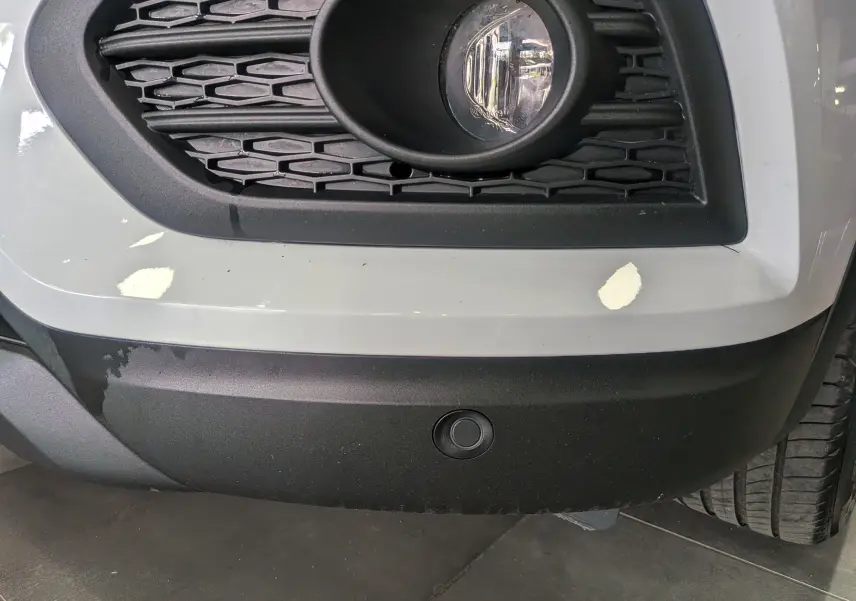 Gros plan sur le pare-chocs avant droit blanc glacier du Renault Kadjar 2021 avec antibrouillard et capteur de stationnement.