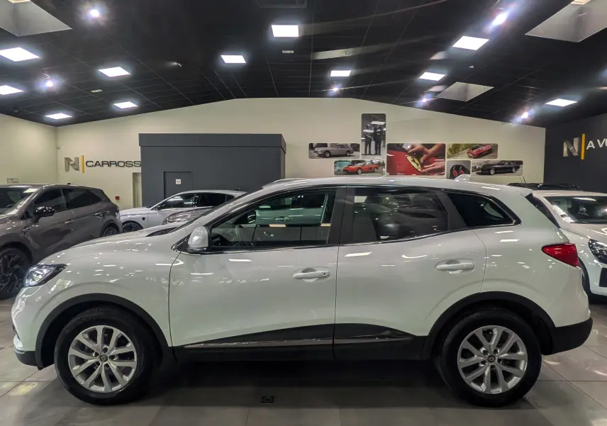 Vue de profil côté gauche d'un Renault Kadjar blanc Glacier 2021 en showroom, soulignant ses jantes alliage et sa silhouette SUV.