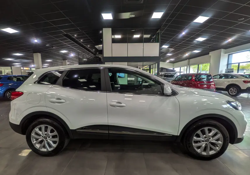 Profil droit d’un Renault Kadjar blanc Glacier 2021 en version Blue dCi 115 CH BUSINESS EDC dans un showroom.