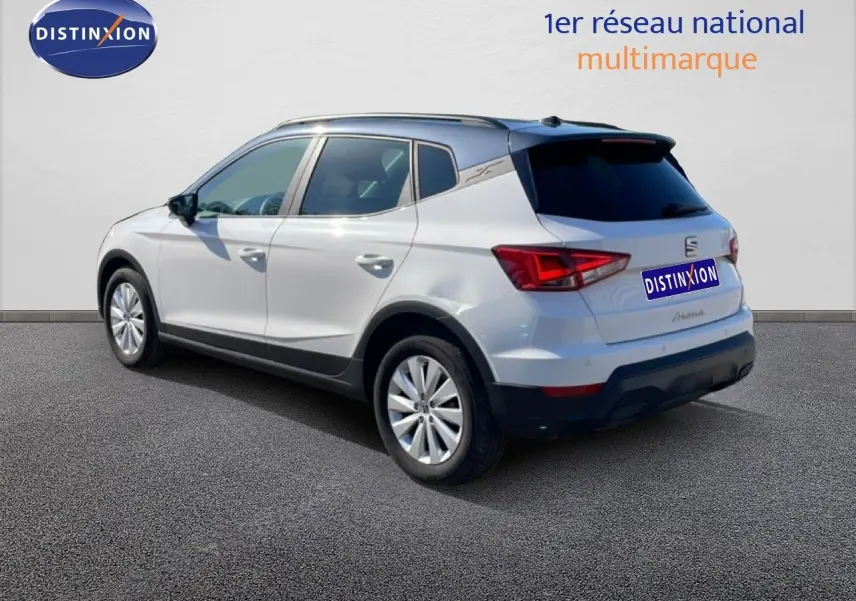Vue 3/4 arrière droite d'un SEAT Arona blanc avec toit gris, mettant en valeur ses lignes modernes et ses feux arrière LED.