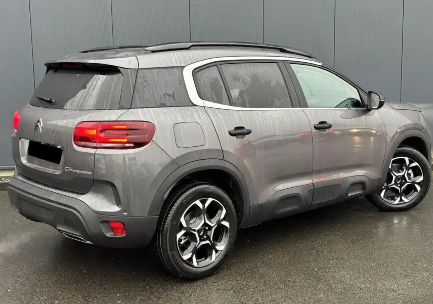 Vue 3/4 arrière droite du Citroën C5 Aircross gris Platinium avec jantes alliage bi-ton et feux arrière LED allumés.