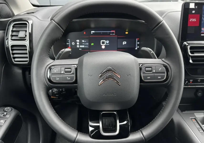 Vue rapprochée du volant cuir noir du Citroën C5 Aircross 2025 avec tableau de bord numérique et commandes intégrées.