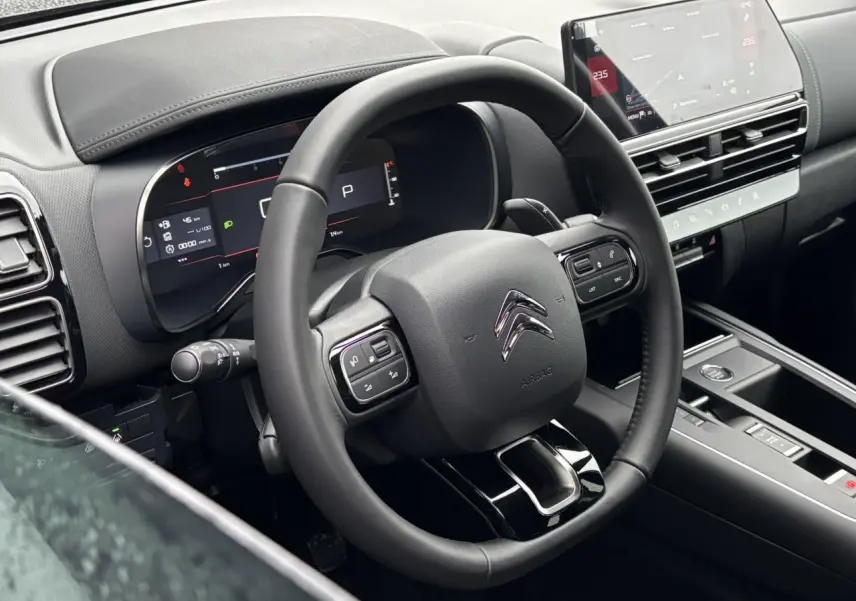Vue intérieure centrée sur le volant noir et le tableau de bord numérique du Citroën C5 Aircross 2025.
