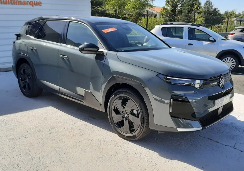 Vue 3/4 avant gauche d'un Citroën C5 Aircross vert Astoria avec toit noir et jantes noires, stationné en extérieur.