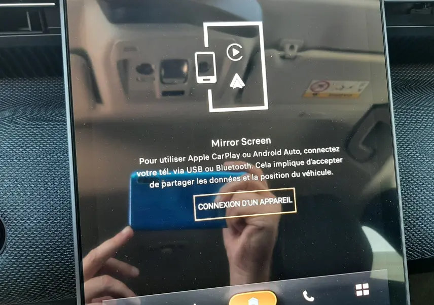 Écran tactile central du Citroën C5 Aircross 2026 affichant la connexion Mirror Screen, avec reflet de mains et tableau de bord noir.