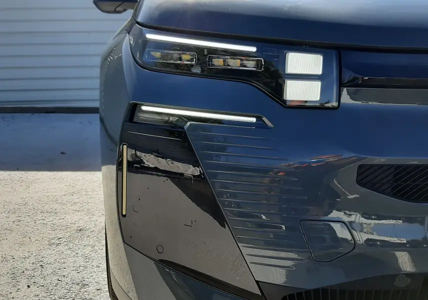 Gros plan sur l'avant gauche du Citroën C5 Aircross 2026 vert Astoria avec toit noir, mettant en valeur ses phares LED distinctifs.