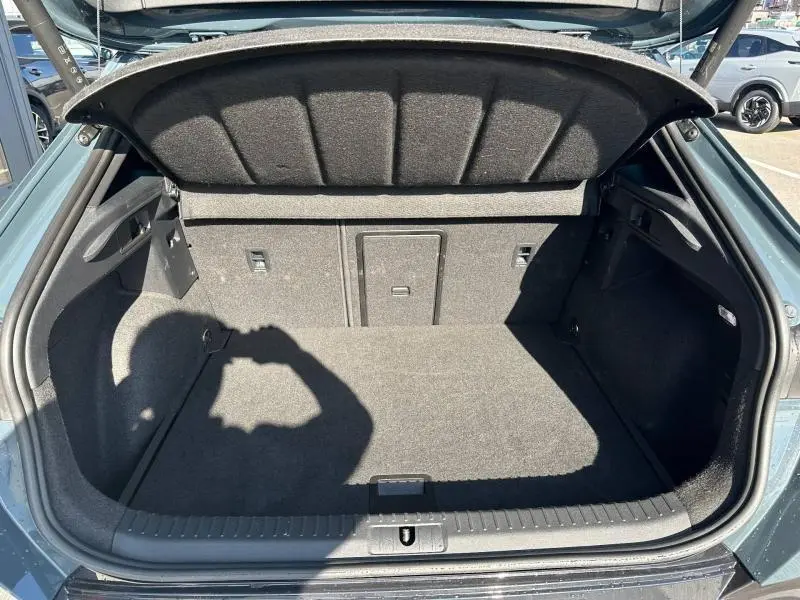 Vue plongeante sur le coffre ouvert du CUPRA Formentor bleu, montrant un espace de rangement propre et bien fini.