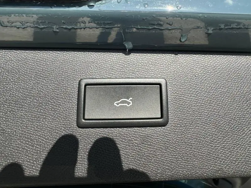 Gros plan sur le bouton d'ouverture électrique du coffre, intérieur noir texturé du CUPRA Formentor bleu.