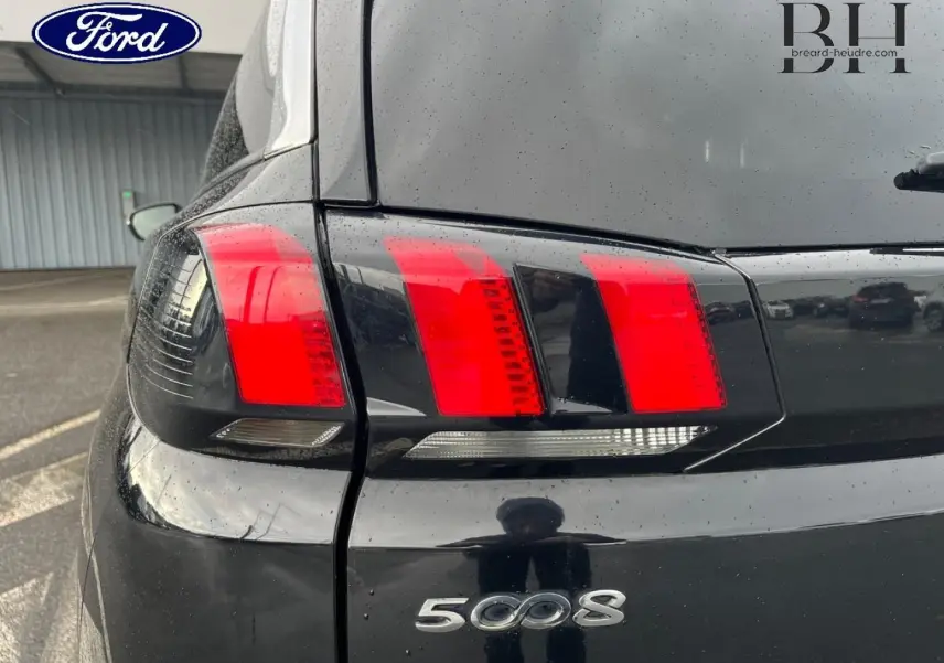 Gros plan sur le feu arrière gauche noir Perla Nera d’un Peugeot 5008 2018 avec logo et reflet sur la carrosserie.