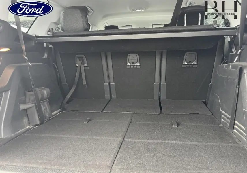 Coffre ouvert d’un SUV noir, vue de l’arrière avec sièges rabattus et banquette arrière visible.