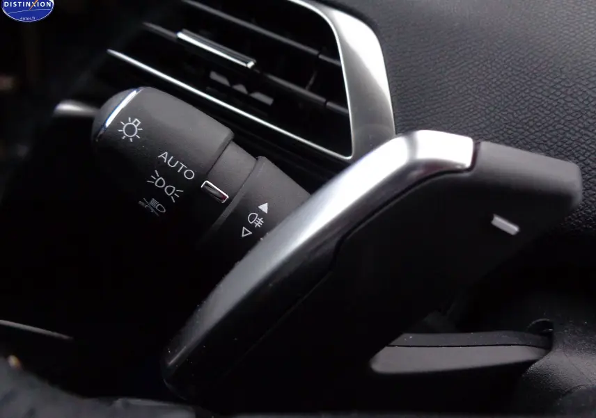 Gros plan sur la manette de commande d’éclairage et le levier de vitesse automatique dans l’habitacle noir du Peugeot 3008 Gris Artense 2023.