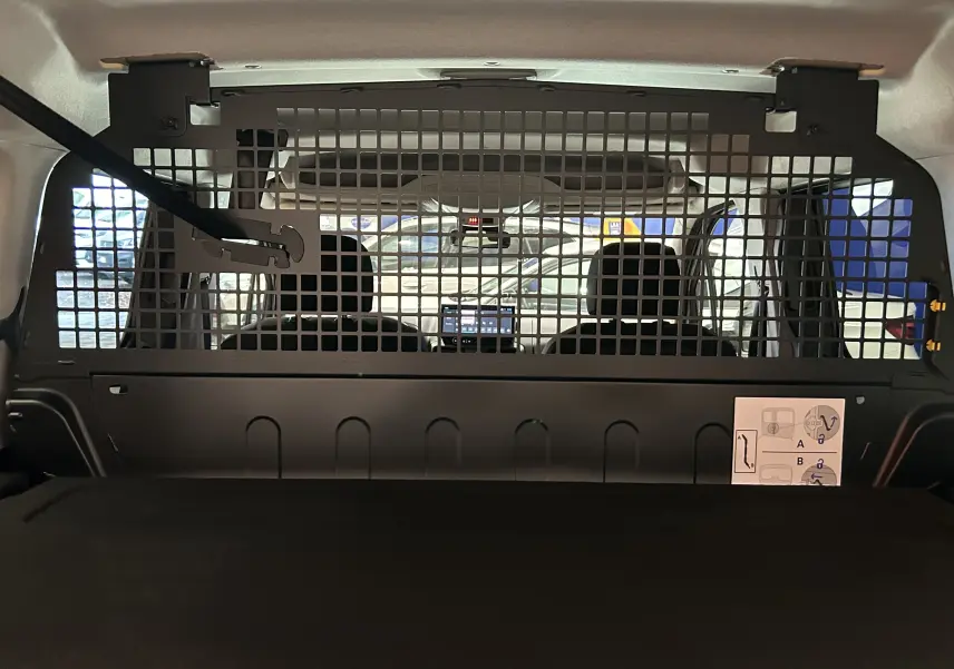 Vue intérieure arrière du Citroën Berlingo Multispace gris Artense, avec séparation grillagée entre coffre et sièges avant.