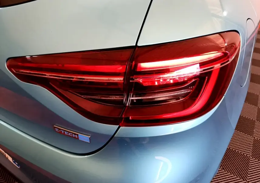 Gros plan sur le feu arrière droit rouge d’une Renault Clio Business E-Tech hybride bleu clair, avec logo E-Tech visible.