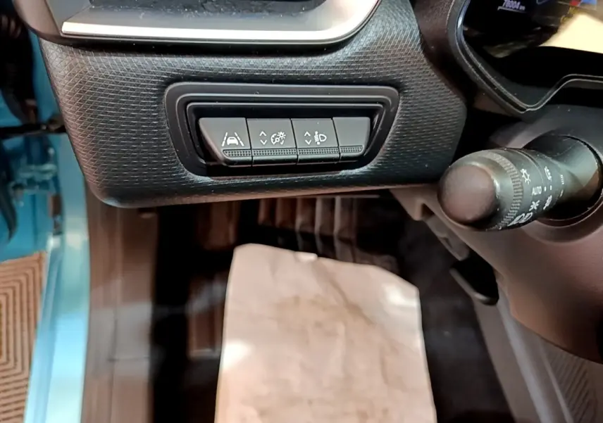 Gros plan sur les commandes d’aide à la conduite sous le tableau de bord côté conducteur d’une Renault Clio bleu hybride 2021.