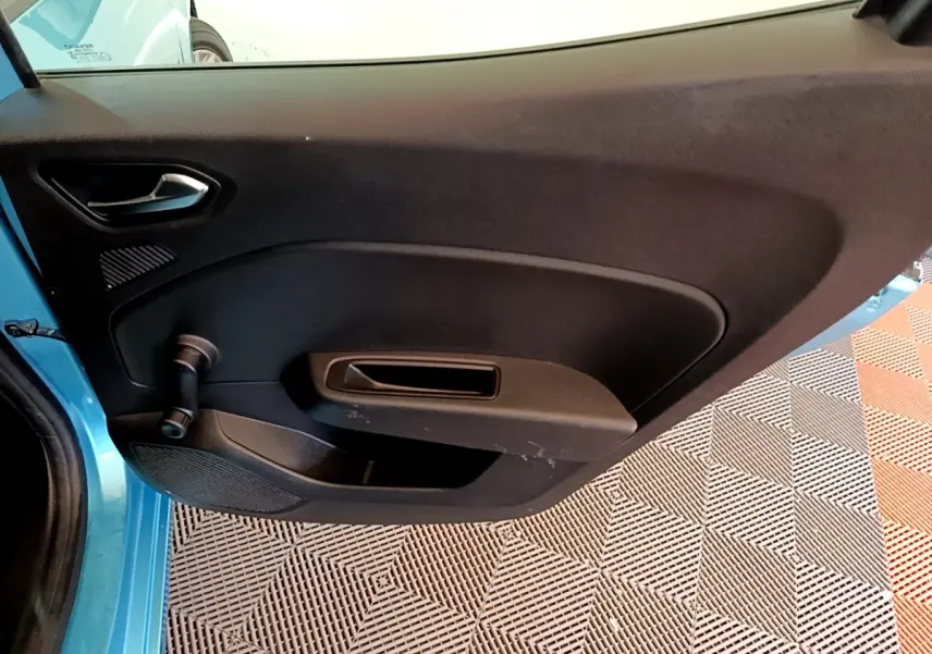 Vue intérieure de la porte avant gauche d'une Renault Clio Business E-Tech hybride bleu, avec poignée et manivelle de vitre.