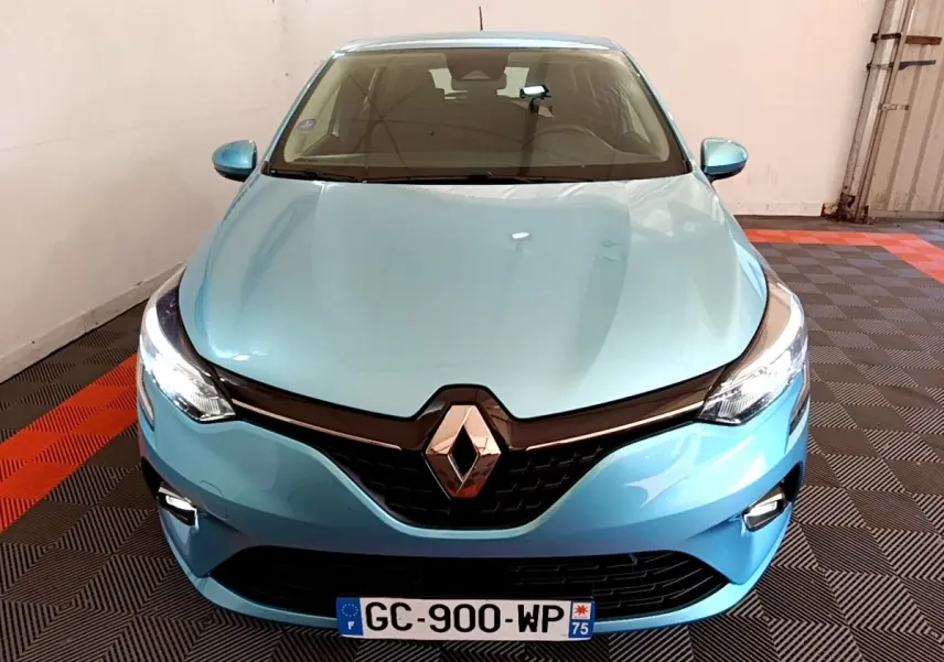 Vue avant rapprochée d'une Renault Clio Business E-Tech hybride bleu clair avec phares LED allumés en intérieur.
