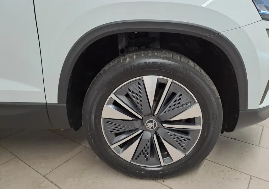Gros plan sur la roue avant droite du Skoda Karoq blanc Lune avec jante alliage au design moderne et logo central.
