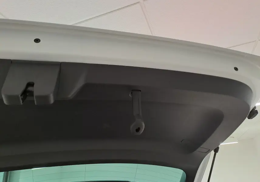Vue rapprochée de l’intérieur du hayon arrière du Skoda Karoq blanc Lune, montrant la poignée de fermeture noire.