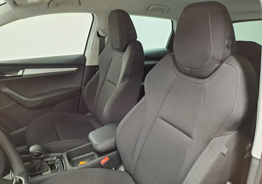 Vue intérieure du côté gauche du Skoda Karoq 2025, sièges avant noirs avec coutures apparentes et console centrale.