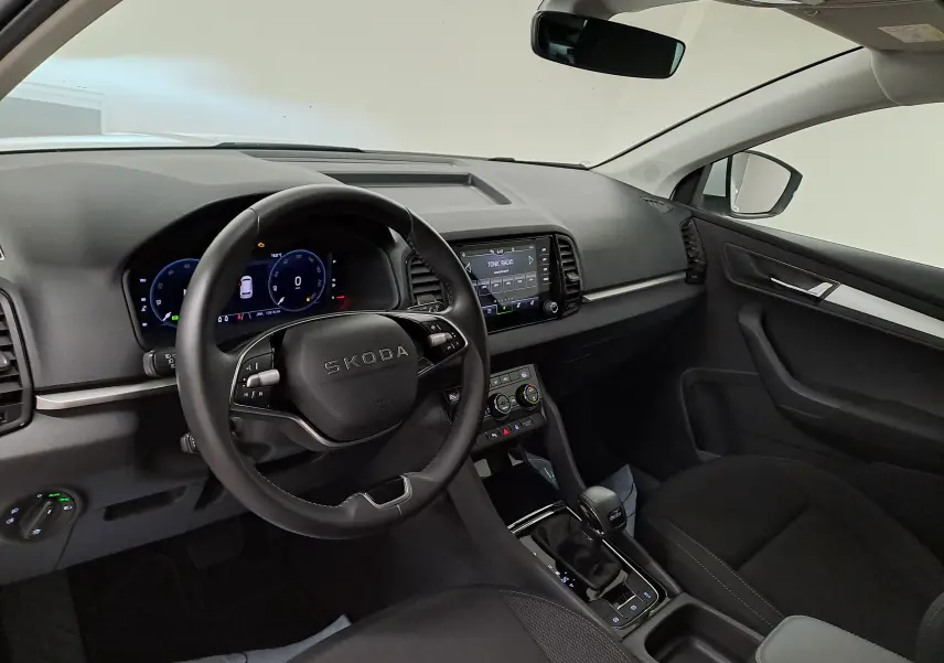 Vue intérieure côté conducteur du Skoda Karoq 2025, tableau de bord noir avec écran tactile et volant multifonction.