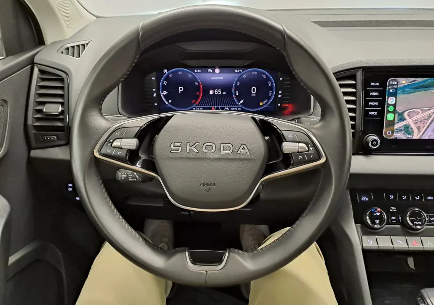 Vue intérieure centrée sur le volant SKODA avec tableau de bord numérique et écran tactile à droite.