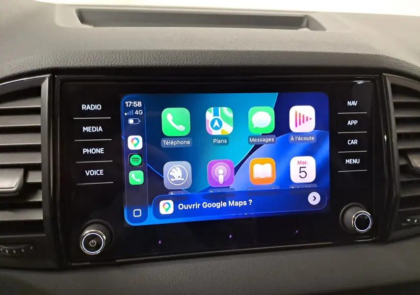 Écran tactile central du Skoda Karoq 1.5 TSI 150 DSG7, affichant Apple CarPlay avec commandes latérales noires.