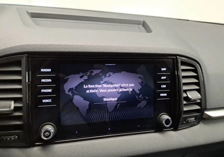 Écran tactile central du Skoda Karoq 2025 affichant un message de navigation, entouré de commandes et grilles d’aération.