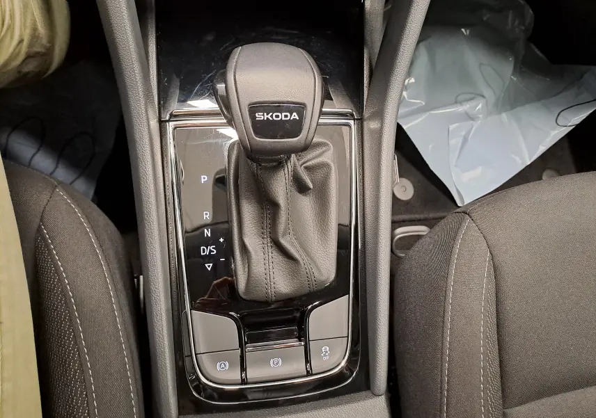 Le levier de vitesses automatique SKODA au centre de la console, entouré de sièges en tissu noir.