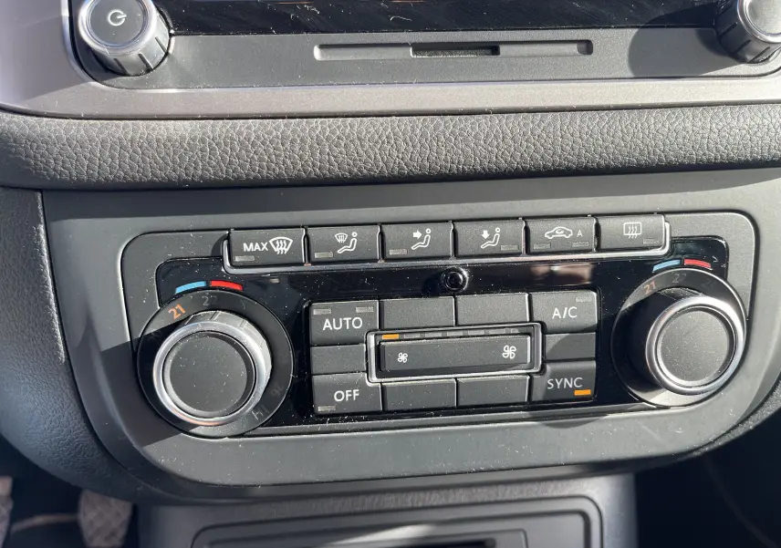 Vue rapprochée du tableau de bord du Volkswagen Tiguan 2015 gris foncé, montrant les commandes de climatisation automatique.