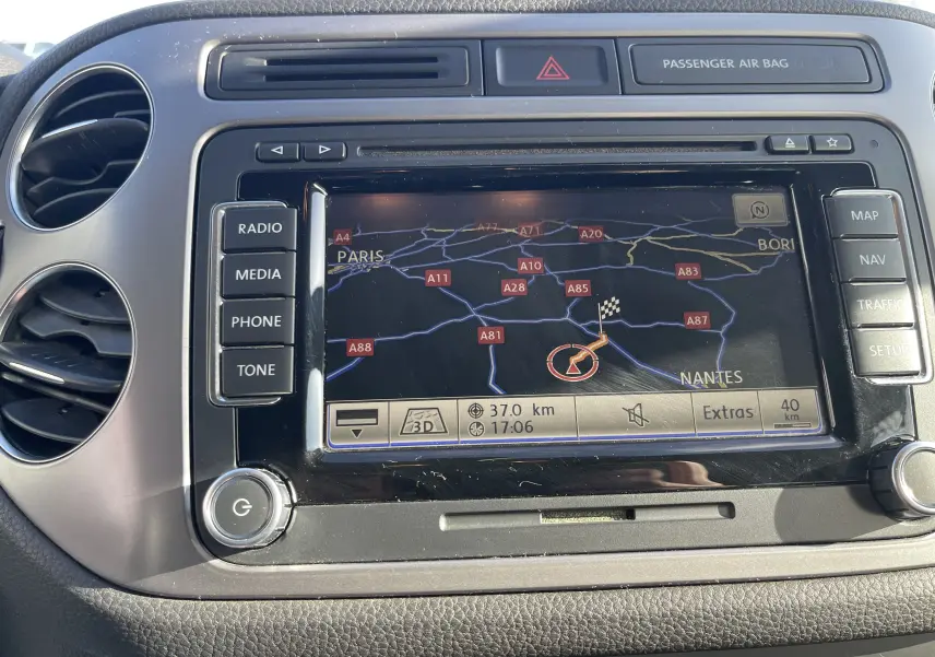 Vue rapprochée du tableau de bord gris foncé du Volkswagen Tiguan 2015, avec écran GPS affichant une carte routière.