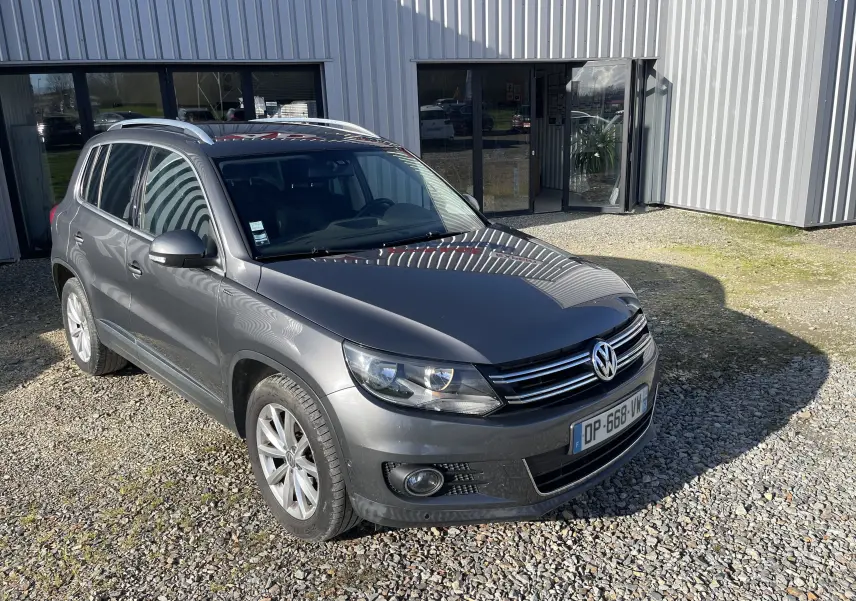 Volkswagen Tiguan gris foncé vu en 3/4 avant droit, avec calandre chromée et jantes alliage.