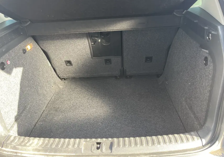 Coffre ouvert du Volkswagen Tiguan gris foncé 2015, vue intérieure montrant l'espace de chargement vide et revêtement en tissu gris.