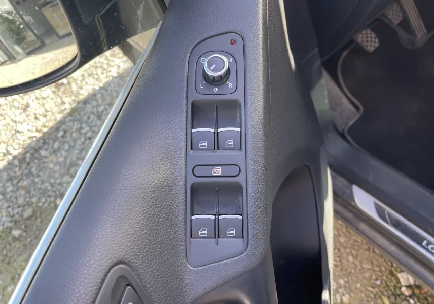 Vue rapprochée du panneau de commandes des vitres et rétroviseurs côté conducteur du Volkswagen Tiguan gris foncé 2015.