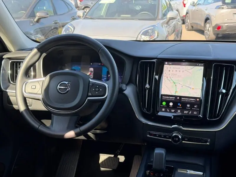 Vue intérieure du tableau de bord et volant cuir noir du Volvo XC60 2024 avec écran tactile central affichant la navigation.
