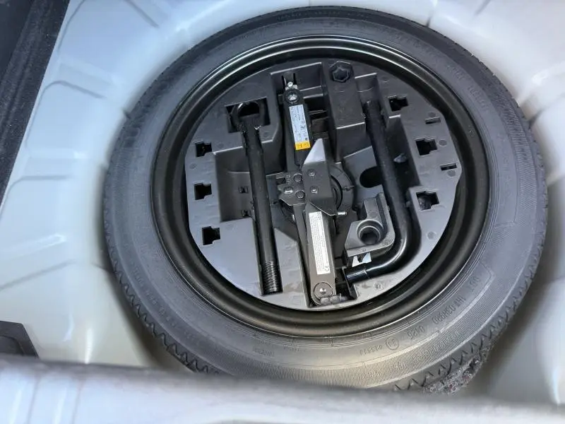 Vue plongeante sur la roue de secours et les outils de bord dans le coffre de la Renault Clio Gris Rafale 2025.
