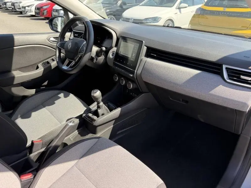 Intérieur avant de la Renault Clio 1.5 dCi 2025, vue côté conducteur, sièges gris et tableau de bord avec écran tactile.