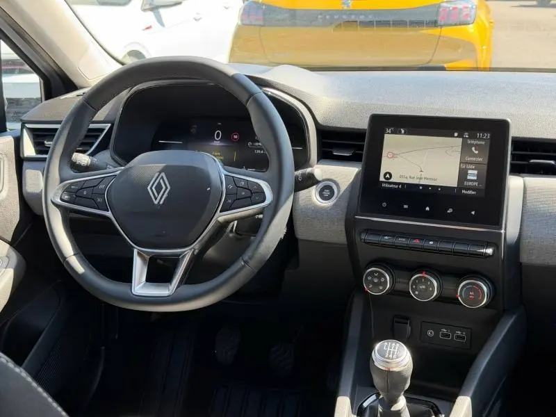 Vue intérieure avant de la Renault Clio gris Rafale 2025, volant multifonction et écran tactile central avec navigation.