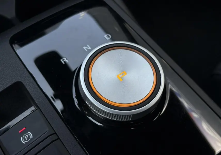 Gros plan sur la molette de sélection de la boîte automatique du MG3 1.5 Hybrid+ blanc, avec éclairage orange autour du mode parking.
