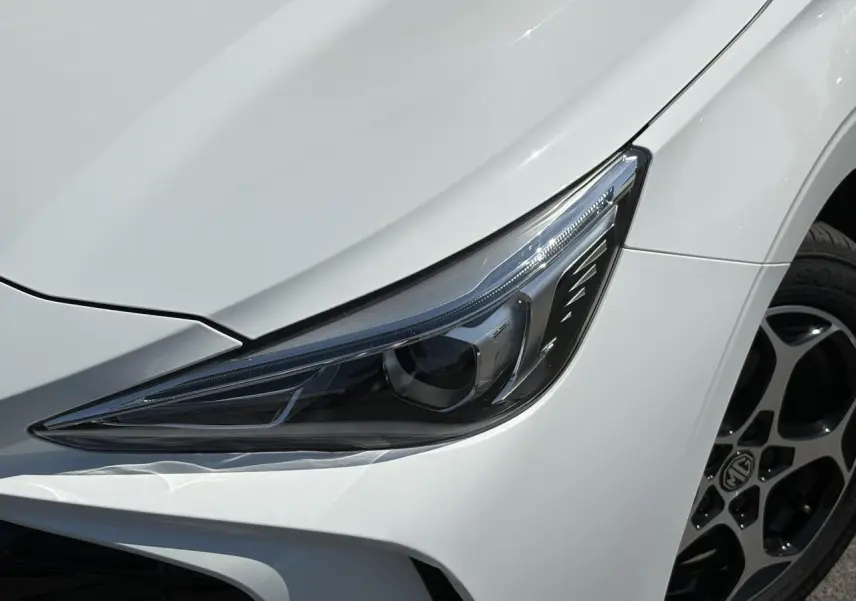 Gros plan sur le phare avant droit blanc Dover du MG3 1.5 Hybrid+ 195 Comfort avec jante alliage 16 pouces.