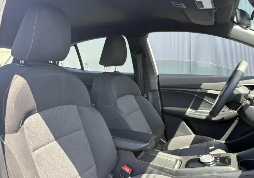 Vue intérieure côté droit du MG3 1.5 Hybrid+ 195 Comfort avec sièges tissu noir et accoudoir central.