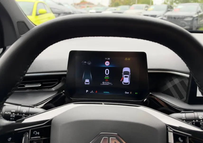 Vue depuis le volant du tableau de bord numérique du MG3 1.5 Hybrid+ 2025 avec affichage couleur et volant cuir noir.