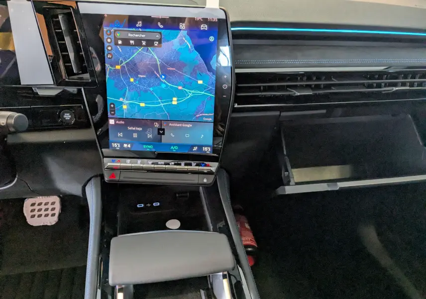 Vue intérieure du tableau de bord du Renault Austral e-tech, avec écran tactile central affichant une carte et boîte à gants ouverte.