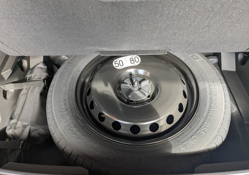 Roue de secours montée dans le coffre du Renault Austral gris schist e-tech full hybrid 2025, hayon motorisé visible.