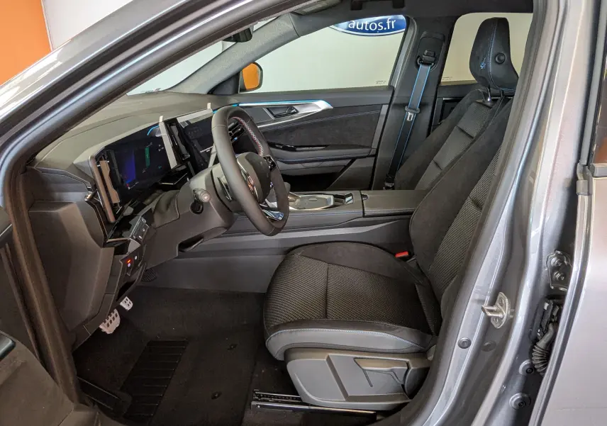 Intérieur côté conducteur du Renault Austral gris schist 2025, sièges noirs avec surpiqûres bleues et tableau de bord digital.
